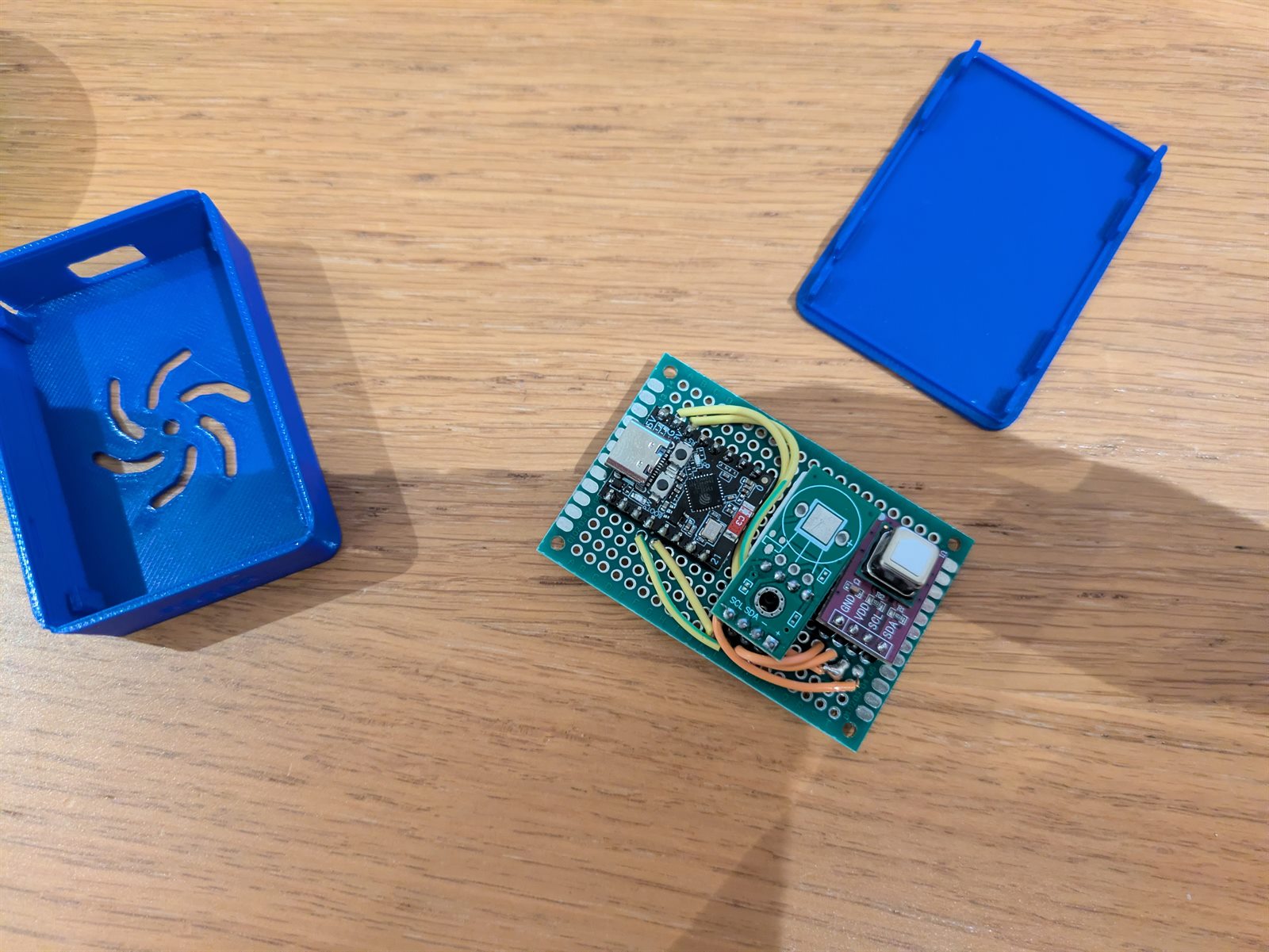 ESP32-C3, temperature and humidity sensor, and CO2 sensor on protoboard beside a blue printed enclosure